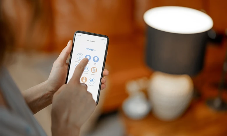 Osoba ovládá chytré osvětlení pomocí aplikace na mobilním telefonu.