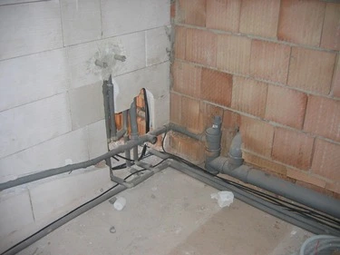 Zobrazuje instalaci kanalizačních trubek v podlahě s viditelným sklonem pro správný odtok.