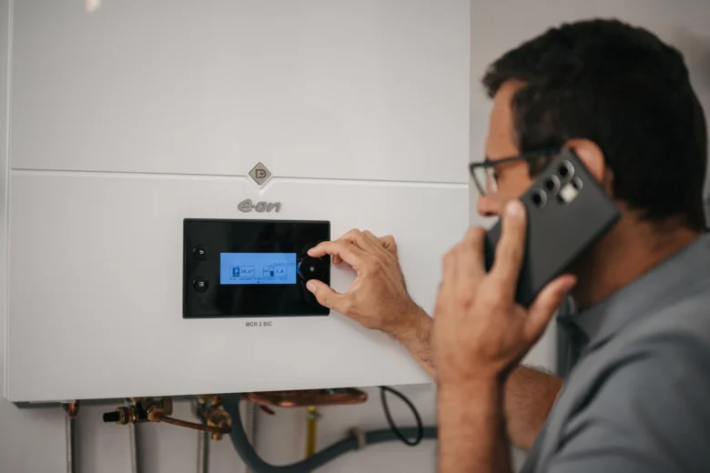 Muž nastavení ovládacího panelu plynového kotle během hovoru na telefonu.