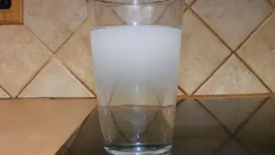 Sklenice s mlékem na tmavém povrchu u dlažby.
