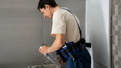 Muž nastavuje hladinu vody v nádržce záchodové mísy.