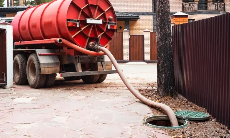 Červená nádrž na žumpa nasává odpad z přístupového otvoru.