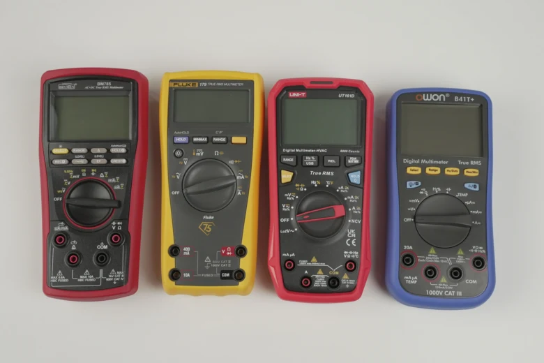 Čtyři digitální multimetry různých značek uspořádané vedle sebe.