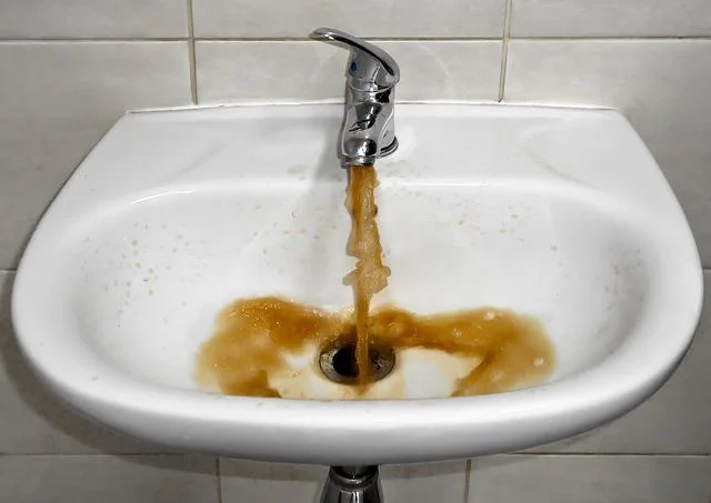 Rezavá voda z kohoutku v umyvadle ukazuje problém s železem.