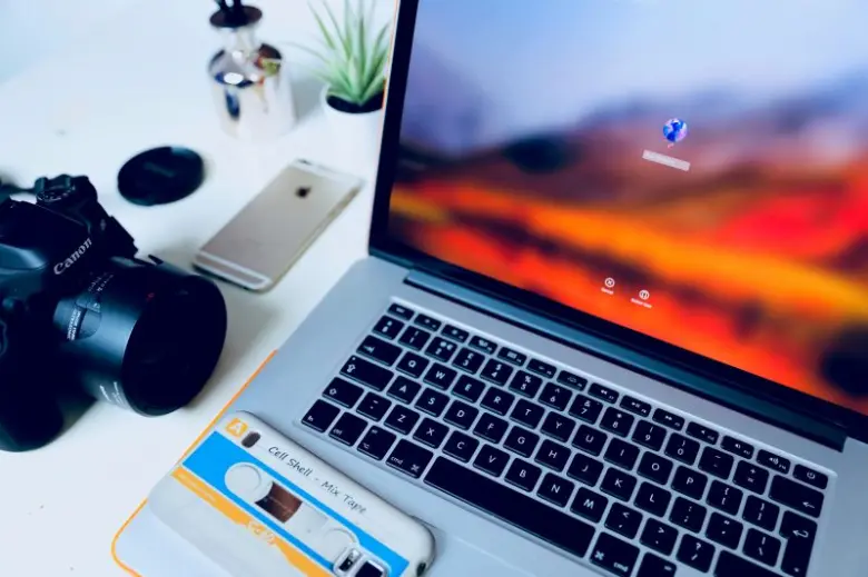 Stříbrný notebook s kamerou na bílém stole.