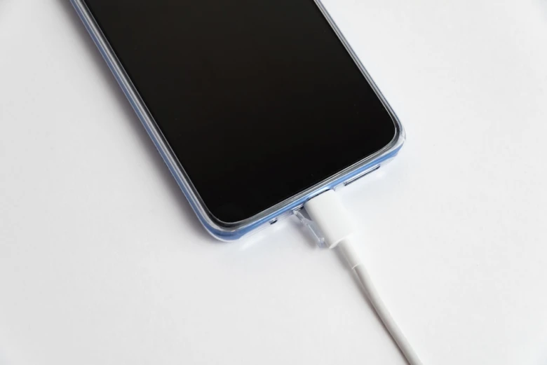 Smartfon nabíjený kabelou na bílém pozadí.