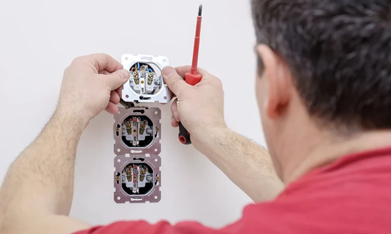 Montáž elektrické zásuvky šroubovákem na bílou stěnu
