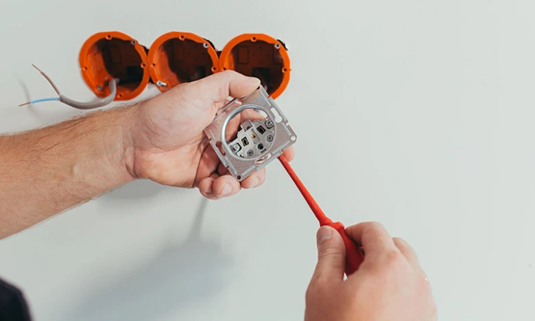 Instalace elektrické zásuvky do zdi pomocí šroubováku.