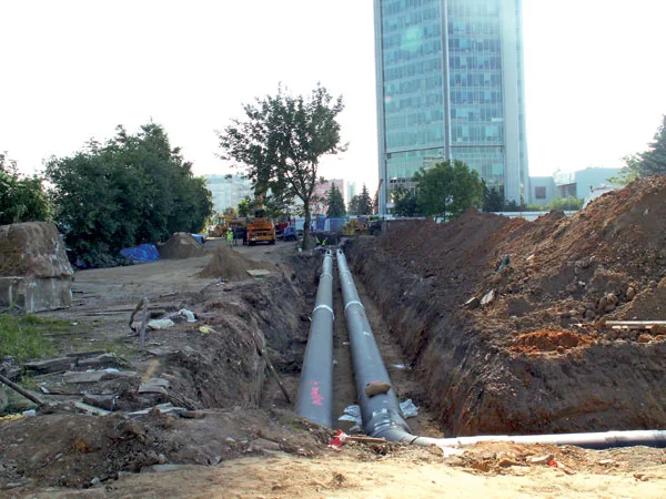 Výkop pro položení plynovodu s dvěma trubkami v městském prostředí.