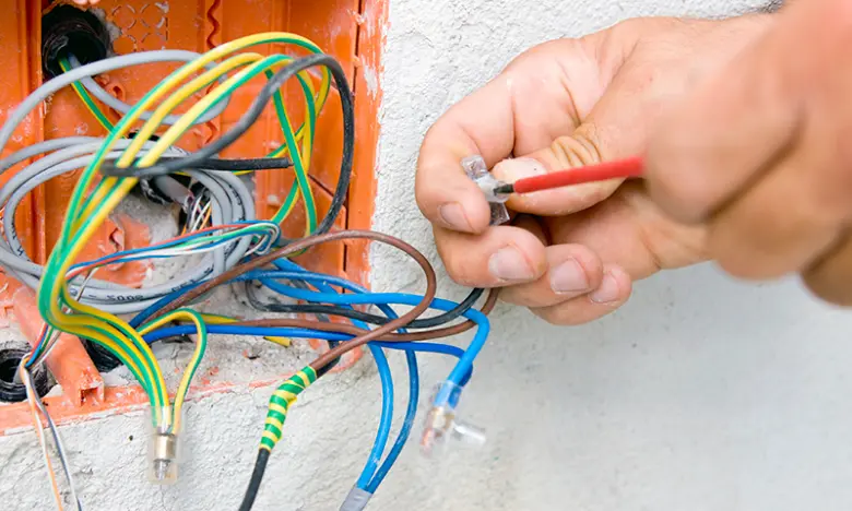Ruka připojuje vodiče v elektrickém rozvaděči.