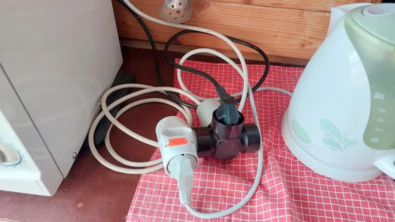 Zamotané elektrické kabely s zástrčkami na kuchyňské desce ukazující nebezpečí.