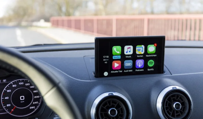 Displej auta s Apple CarPlay ukazující ikony aplikací jako telefon, hudba a mapy.