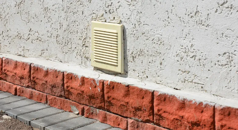 Žlutý ventilátor na zdi garáže pro větrání.