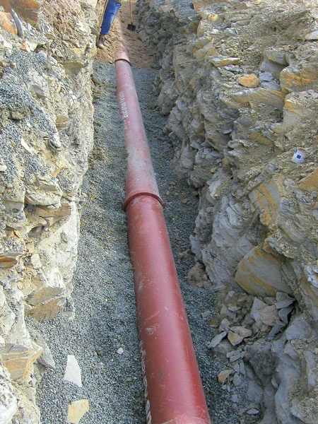Červená kanalizační trubka v jámě pro instalaci.