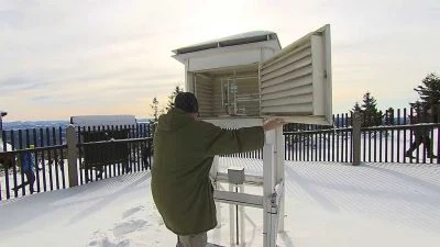 Muž upravuje přístroje v meteorologické stanici ve sněhu.
