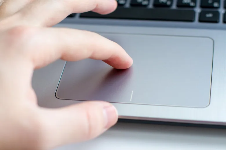 Ruka používá touchpad na notebooku pro ilustraci funkce.