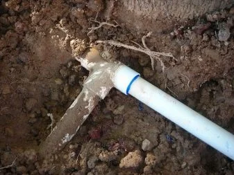 Poškozená bílá plastová trubka v zemi po zamrznutí vody.