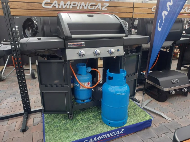Plynová lahev u grilu vystavená slunci na prodejně.