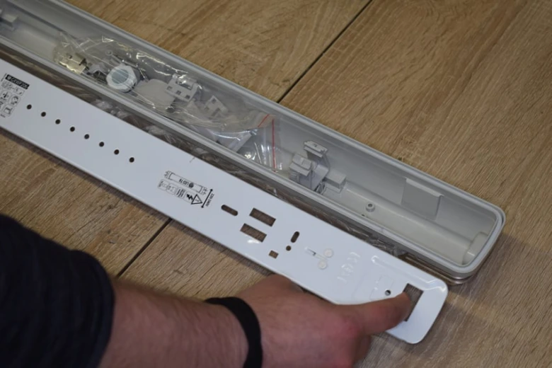 Bílá základna pro instalaci LED trubice s viditelnými součástkami.