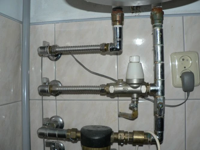 Zobrazení vodovodních potrubí a ventilů bojleru v koupelně.