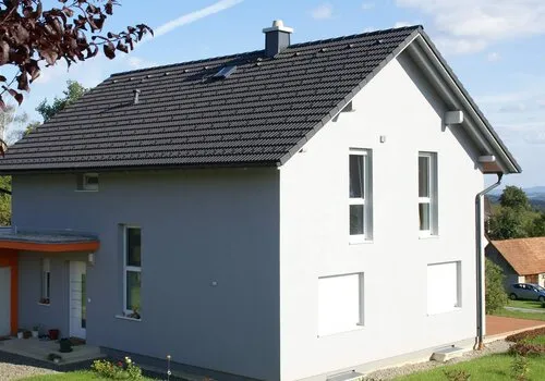 Dům s komínem na střeše poblíž oken.