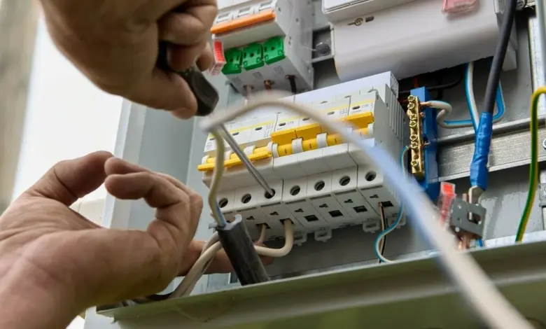 Elektrikář upravuje třífázový jistič v rozvaděči.