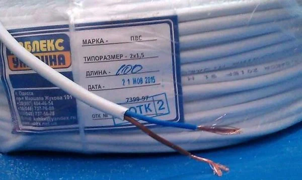 Bílý elektrický kabel s viditelnými vodiči a technickými údaji na štítku.