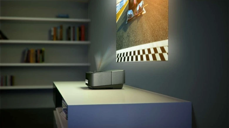 Digitální projektor na stole v interiéru s promítaným obrázkem.