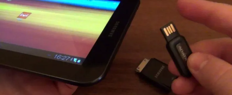 Ruka drží USB disk vedle tablety s displejem.