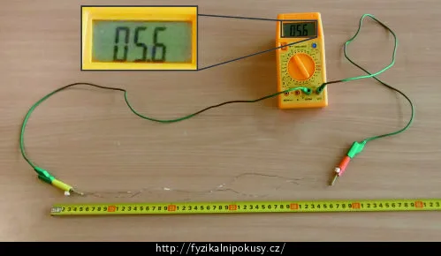Multimetr měří odpor drátu vedle pravítka.