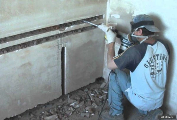 Stavebník řezá drážku do zdi pro elektroinstalaci.