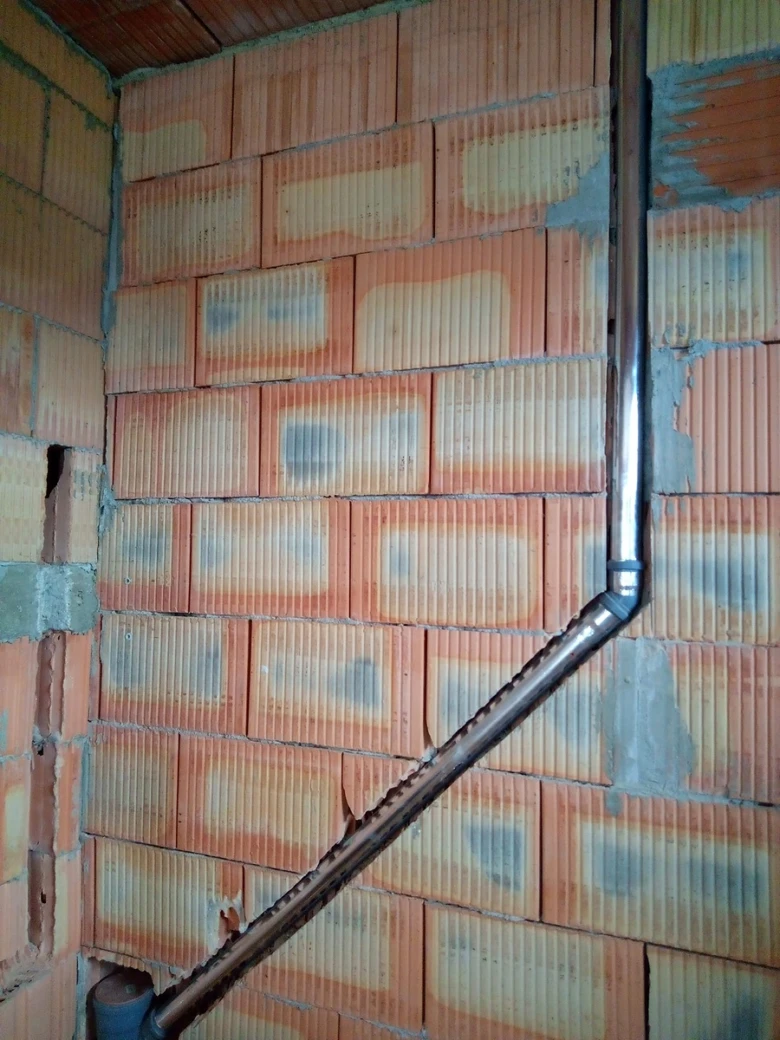 Viditelný vodovodní potrubí v nezdi z cihel.