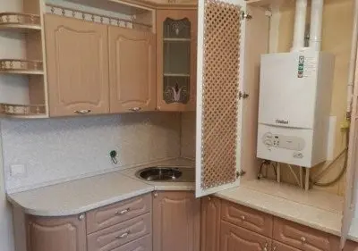 Plynový kotel skrytý v kuchyňském šuplíku za roletou.