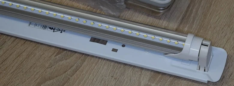 Bílá LED trubice na dřevěné podložce s viditelnými diodami.