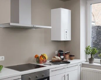 Kuchyň s elektrickým průtokovým ohřívačem vody pod skříní.