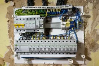 Otevřený elektrický rozvaděč s viditelnými vodiči v bytovém domě.