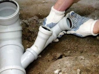 Ruční instalace sklonu kanalizačního potrubí z PVC v jámě.