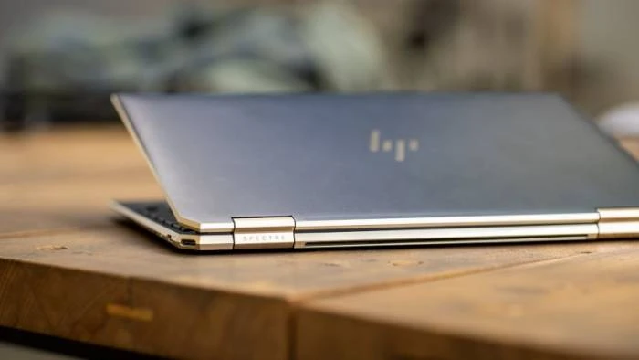 Stříbrný notebook v uzavřeném stavu na dřevěné ploše.