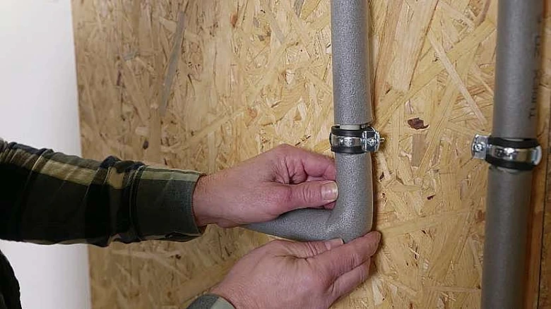 Ruční instalace izolovaného plynového potrubí s hrdlem na zdi.