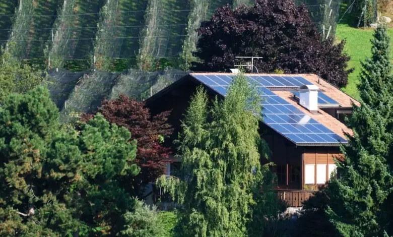 Dům s fotovoltaickými panely na střeše v krajině.