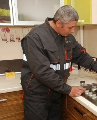 Muž připojuje plynový sporák v kuchyni.