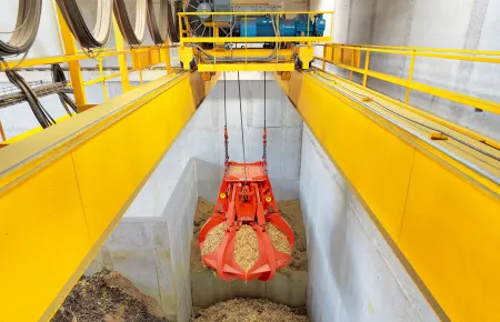 Oranžová lopata s pelety z dřeva nad betonovým silo.