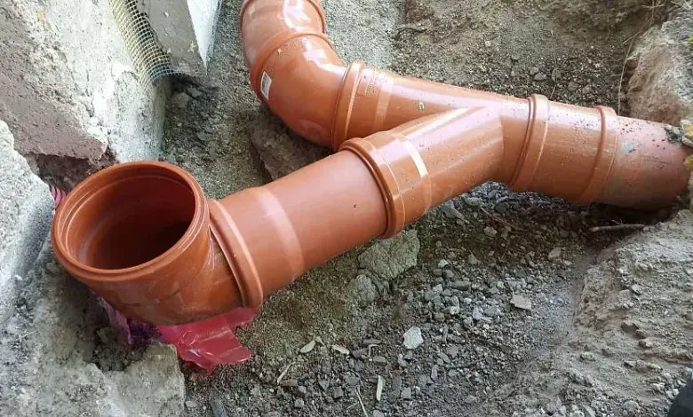Oranžové odpadní trubky v zemi během instalace.