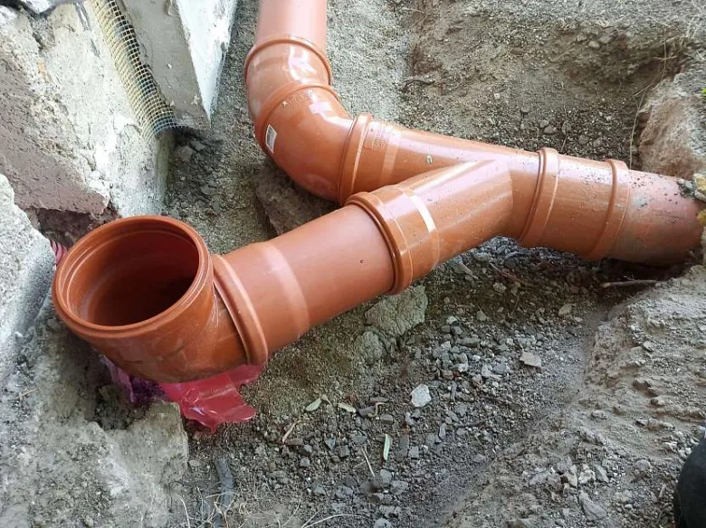 Oranžové odpadní trubky v zemi během instalace.