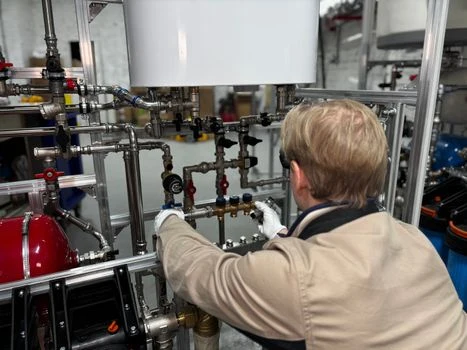Technik pracuje s trojcestnými ventily v průmyslovém potrubním systému.