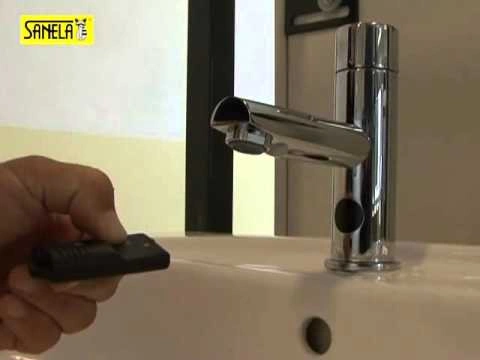 Ruka drží dálkový ovladač pro splachování pisoáru.