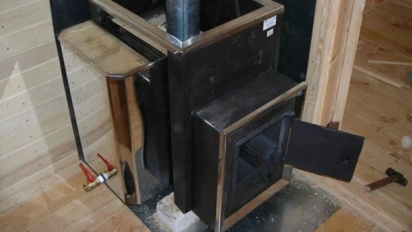 Instalace kovového kamna ve vaně s viditelnými potrubími.