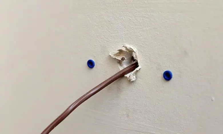 Kabel prochází otvorem ve zdi s modrými úchyty pro ukotvení.