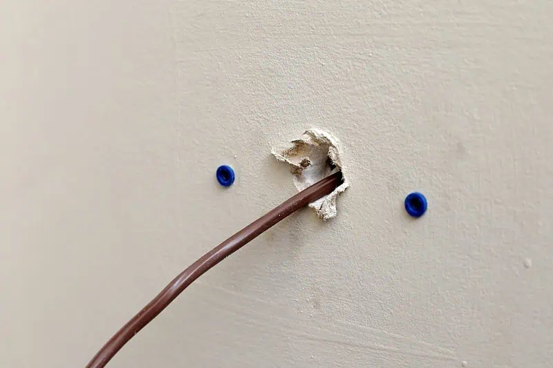 Kabel prochází otvorem ve zdi s modrými úchyty pro ukotvení.