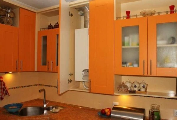 Plynový kotel skrytý v kuchyňském šuplíku za otevřenou dveří.